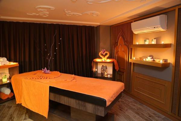 Massageraum im J'adore Deluxe Hotel & Spa mit orangem Handtuch und Kerzen.