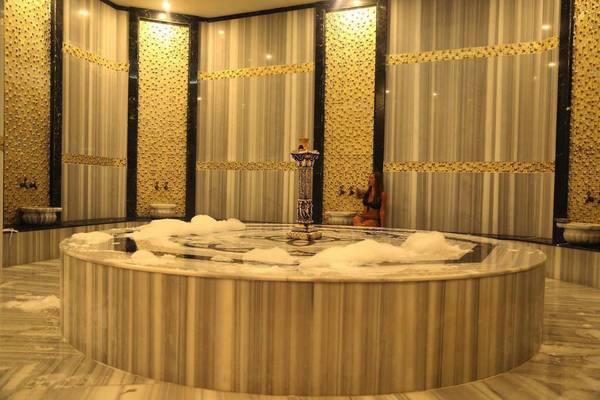 Dampfbad im J'adore Deluxe Hotel & Spa mit einer Frau, die neben dem zentralen Brunnen sitzt.
