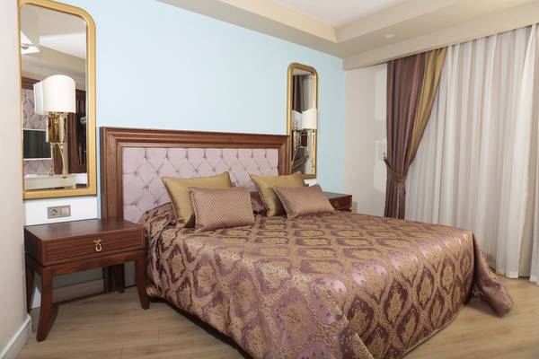 Schlafzimmer im J'adore Deluxe Hotel mit blauen Wänden, großen Spiegeln und einem Doppelbett.
