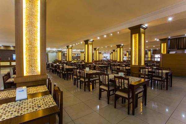 Innenansicht des Restaurants im Eftalia Holiday Village mit gedeckten Tischen und gelben Säulen.