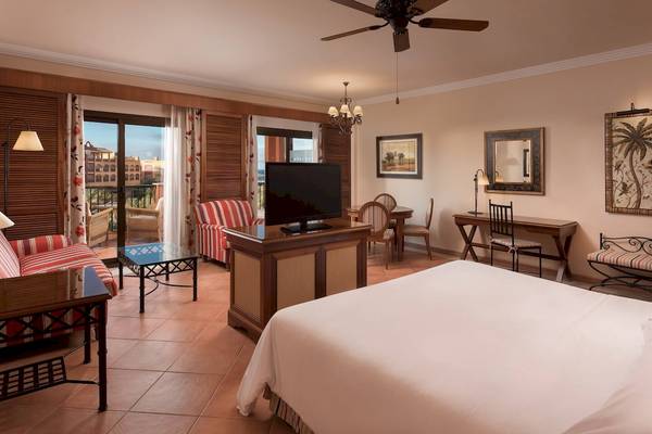 Schlafzimmer im Sheraton Fuerteventura Beach, Golf & Spa Resort mit Fernseher, Couch, Tisch und Möbeln.