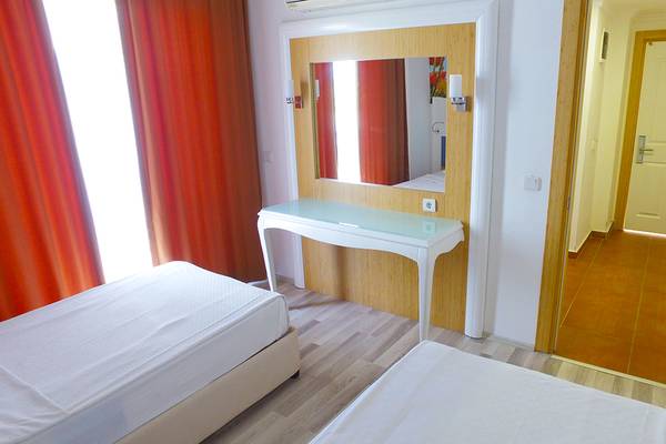 Doppelzimmer im Eftalia Holiday Village mit zwei Betten, einem Tisch und einem Spiegel.