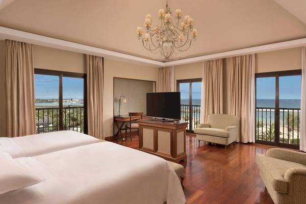 Hotelzimmer im Sheraton Fuerteventura Beach, Golf & Spa Resort mit zwei Betten, Fernseher und Balkon mit Meerblick.