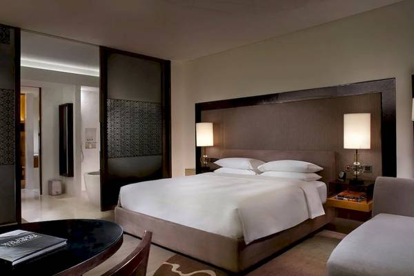 Schlafzimmer im Park Hyatt Abu Dhabi Hotel & Villas mit Doppelbett, Nachttischen, Lampen und einem Sofa.