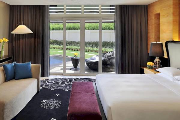 Suite-Innenraum im Park Hyatt Abu Dhabi Hotel & Villas mit Gartenblick, Sofa und Bett.