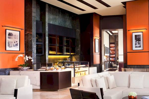 Lobby des Park Hyatt Abu Dhabi Hotel & Villas mit weißen Möbeln und orangefarbenen Wänden.