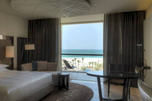 Suite im Park Hyatt Abu Dhabi Hotel & Villas mit Meerblick, inklusive Bett, Sofa, Tisch und Fenster mit Ausblick auf den Strand.