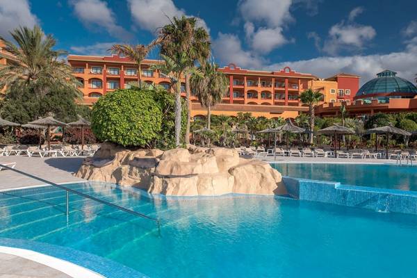 Außenbereich des Sheraton Fuerteventura Strand und Pool mit Loungestühlen und Palmen