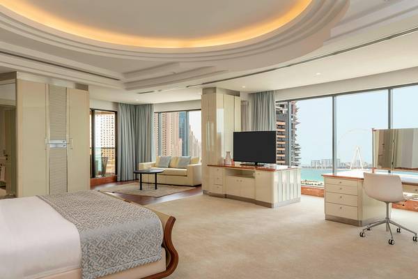 Innenansicht einer Suite im Le Royal Meridien Beach Resort mit Bett, Wohnzimmer und Schreibtisch.
