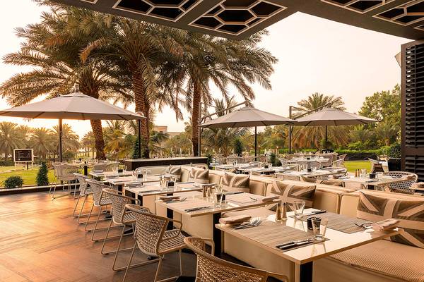 Außenterrasse des Le Royal Meridien Beach Resort mit Tischen und Stühlen unter Sonnenschirmen.