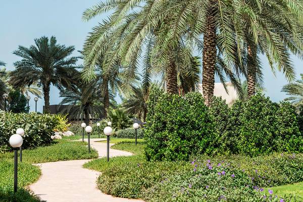 Gartenweg im Le Royal Meridien Beach Resort & Spa mit Palmen und Laternen.