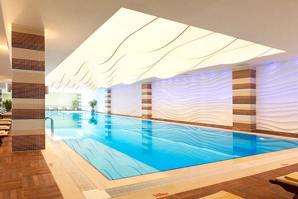 Innenpool im Paloma Oceana Hotel mit Wellenmuster an den Wänden und gefliestem Boden.