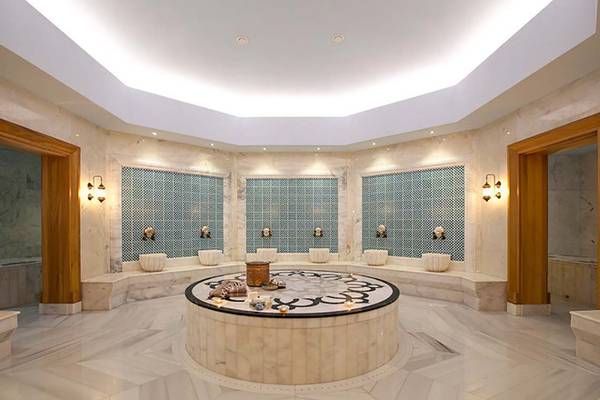 Innenbereich des Hammams im Paloma Oceana Hotel mit Marmorboden, weißen Wänden und blauen Mosaikfliesen.