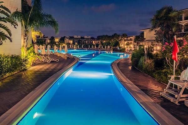 Schwimmbad bei Nacht im Paloma Oceana Hotel mit blauem Wasser und beleuchteten Liegen