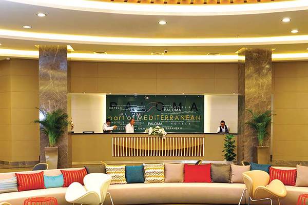 Empfangsbereich des Paloma Oceana Hotels mit bunten Kissen und Pflanzen.