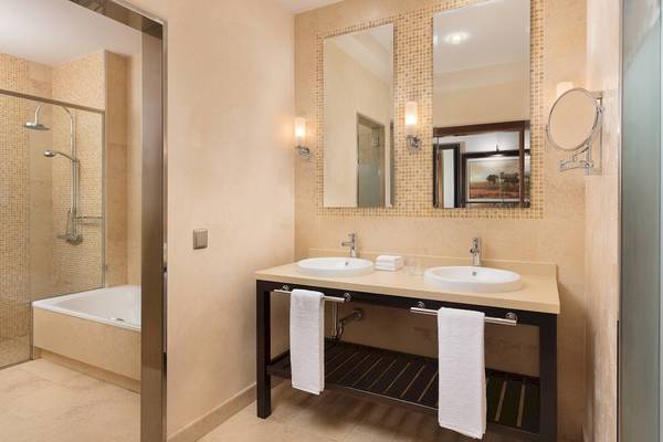 Badezimmer im Sheraton Fuerteventura Beach, Golf & Spa Resort mit zwei Waschbecken, Spiegeln und Handtüchern.