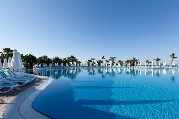 Außenpool im Paloma Oceana Hotel mit blauen Liegen und weißen Sonnenschirmen