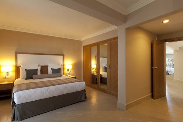 Innenansicht eines Schlafzimmers im Paloma Oceana Hotel mit Doppelbett, Nachttischen und Kleiderschrank.