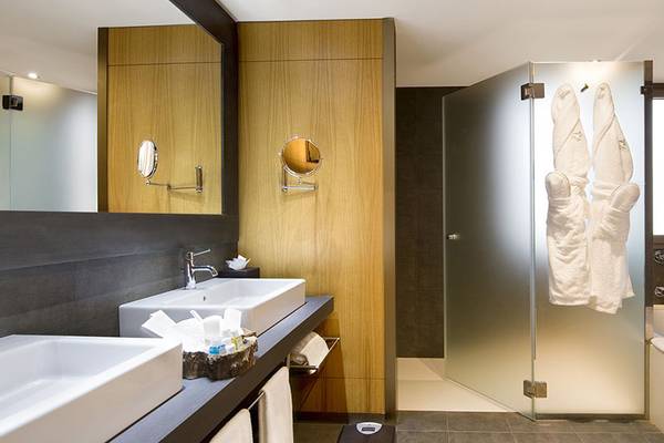 Ein Badezimmer im Lopesan Baobab Resort mit zwei Waschbecken, einer Glasdusche und einem Badewanne.