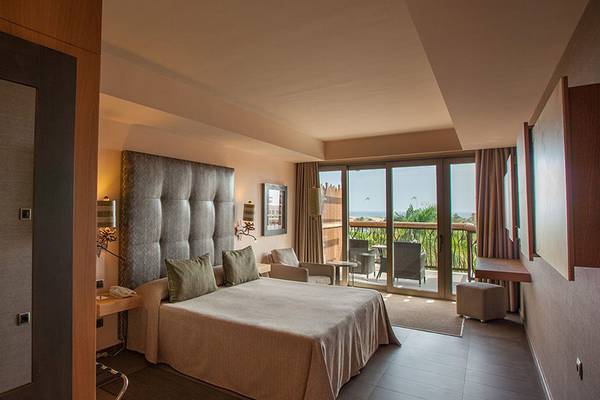 Innenansicht eines Hotelzimmers im Lopesan Baobab Resort mit Doppelbett und Terrassenzugang.