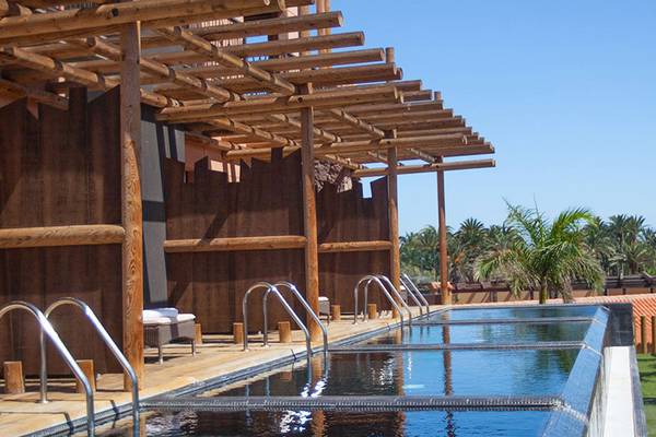 Poolbereich des Lopesan Baobab Resorts mit hölzerner Pergola und Blick auf Palmen