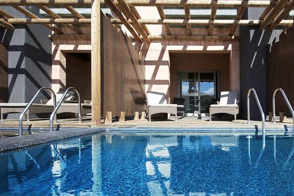 Pool-Terrasse im Lopesan Baobab Resort mit Sonnenliegen und Pergola.