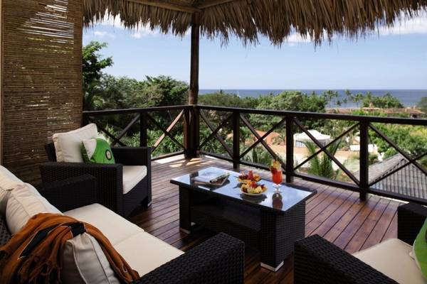 Terrasse des Jardin del Eden Boutique Hotels mit Blick auf das Meer und Palmen.