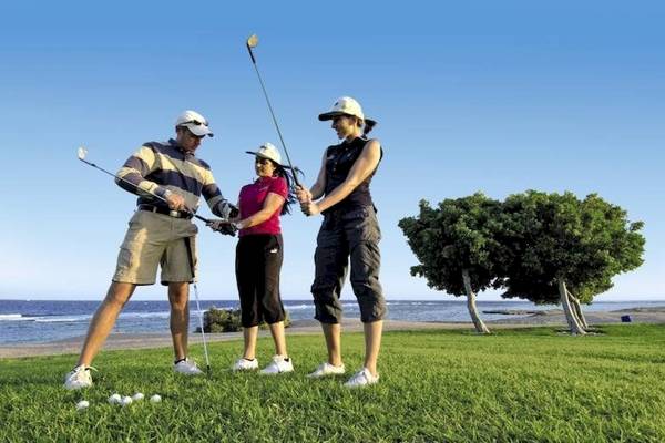 Drei Golfspieler am Strand mit Blick auf das Meer.