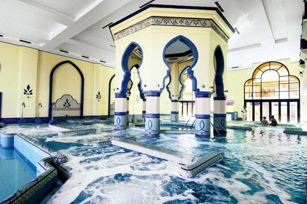 Der Poolbereich im Cascades Golf Resort Spa & Thalasso mit blauen und gelben Säulen.