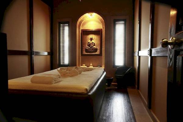 Massage-Behandlungsraum im Cascades Golf Resort Spa & Thalasso mit Liege, Kissen, Fenstern und Buddha-Bild