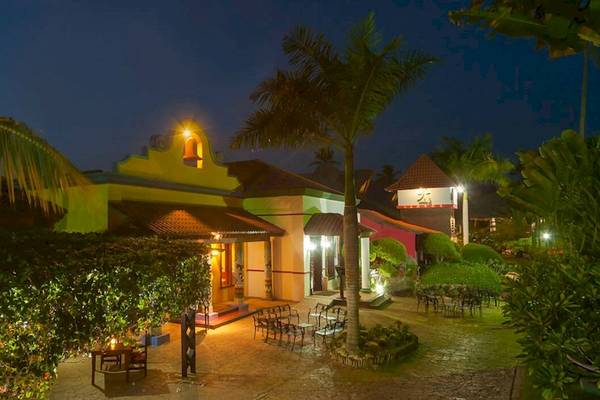 Nachtansicht des Caribe Deluxe Princess Hotels mit beleuchteter Fassade und Außenbereich mit Tischen und Stühlen.