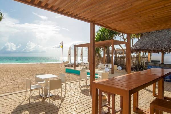 Außenbereich des Caribe Deluxe Princess Hotels mit Blick auf den Strand, Sonnenliegen und eine Bar.