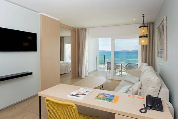 HSM Golden Playa Hotel Zimmer mit Meerblick, Fernseher, Schreibtisch, Sessel und Balkon mit Tisch und Stühlen.