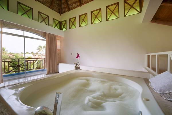 Badezimmer einer Suite mit Badewanne, Balkon und tropischem Ausblick.