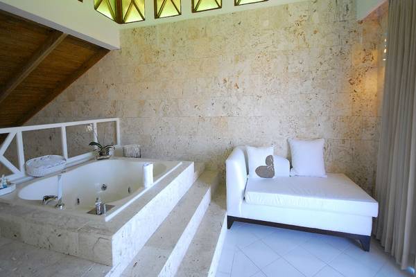 Ein Badezimmer mit einem Whirlpool und einem weißen Sofa neben einer Marmorwand.