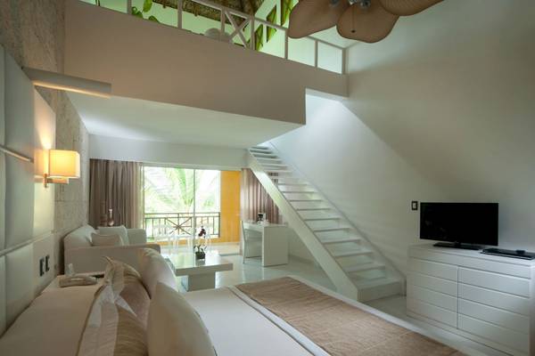 Innenansicht eines Zimmers im Caribe Deluxe Princess Hotel mit Bett, Fernseher und Treppe.