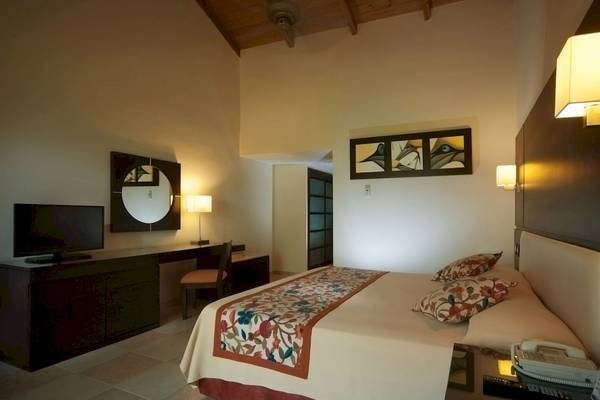 Hotelzimmer im Caribe Deluxe Princess Hotel mit Bett, Fernseher, Schreibtisch und Lampe.