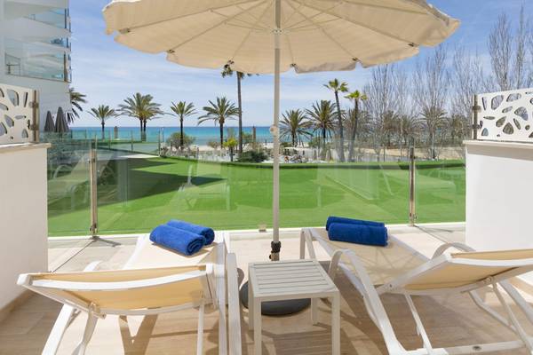 Balkonblick des HSM Golden Playa Hotels mit Sonnenschirm, Liegestühlen, grünem Golfplatz und Meer.