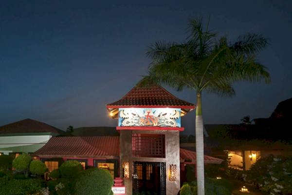 Die Außenansicht des Caribe Deluxe Princess Hotels bei Nacht mit beleuchteten Gebäuden und Palmen.