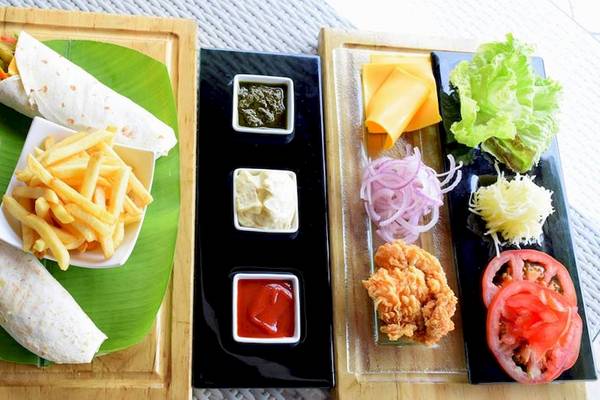 Essen Angebot des Hotels Tamassa Bel Ombre mit einem Burrito, Pommes, und Salat auf einem Blatt serviert.
