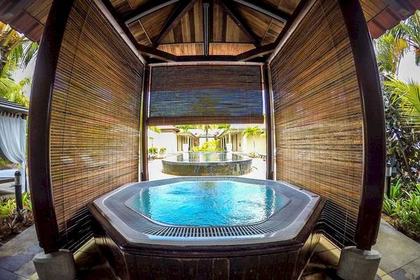 Außen-Whirlpool des Tamassa Bel Ombre Hotels mit umliegenden Pflanzen und Gebäuden.