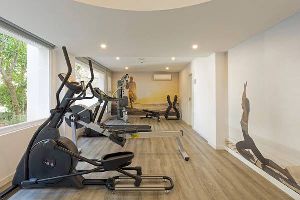 Fitnessbereich im HSM Golden Playa Hotel mit Geräten und großen Fenstern.