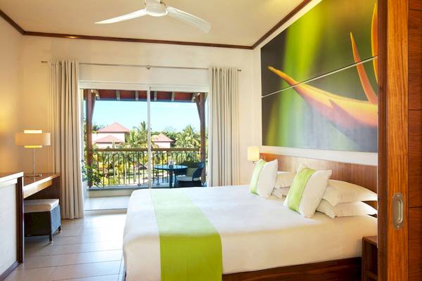 Schlafzimmer im Tamassa Bel Ombre Hotel mit großem Bett und Aussicht auf den Balkon.