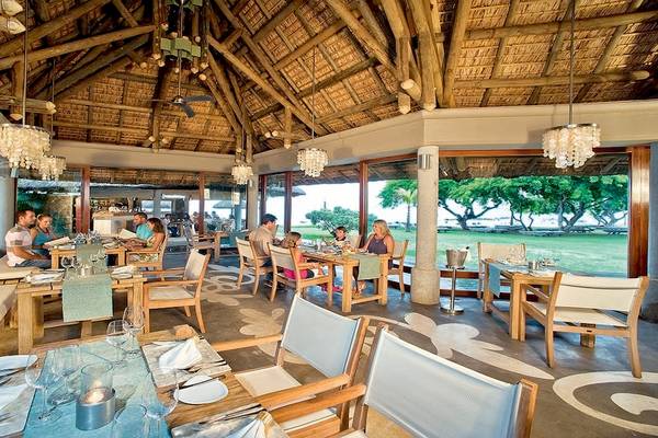 Innenansicht des Restaurants des Tamassa Bel Ombre Hotels mit Gästen, die an Tischen sitzen.
