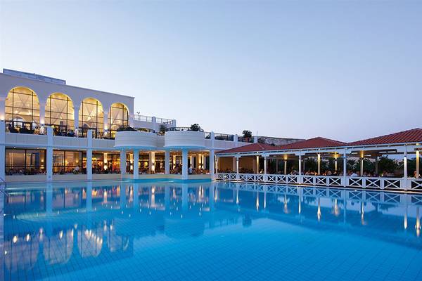 Außenpoolbereich des Porto Bello Royal Hotels am Abend mit Gästen, die in der Lounge sitzen.