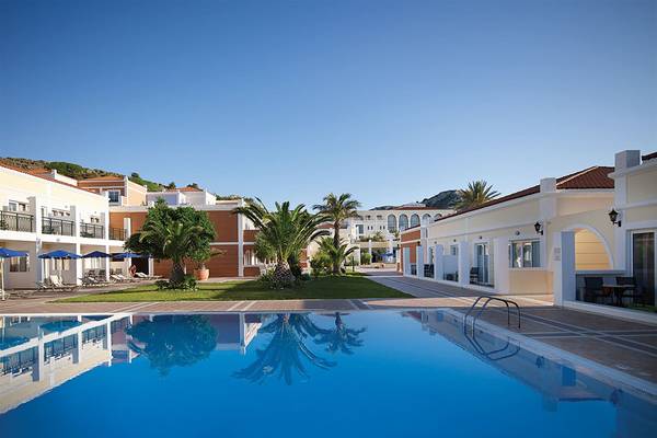 Außenpool des Porto Bello Royal Hotels mit Gebäuden und Palmen im Hintergrund.
