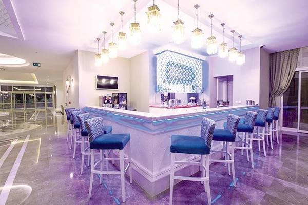 Bar im Diamond Elite Hotel & Spa mit lila Beleuchtung und blauen Stühlen.