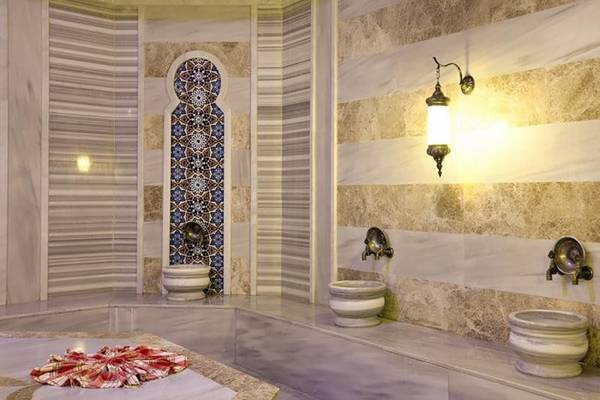 Innenbereich des Diamond Elite Hotel & Spa mit Marmorwänden, dekorativen Lampen und drei Waschbecken.