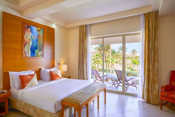 Hotelzimmer im Parrotel Beach Resort mit Doppelbett, Balkon und Blick auf die Palmen