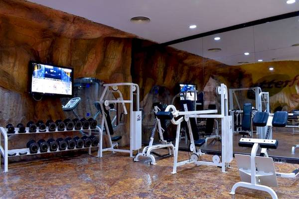 Fitnesscenter im Parrotel Beach Resort mit verschiedenen Geräten und einer steinernen Wand.